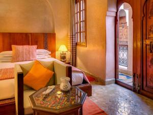 马拉喀什Marrakech Riads, Angsana Heritage Collection的一间卧室配有一张床和一张桌子,上面有花瓶