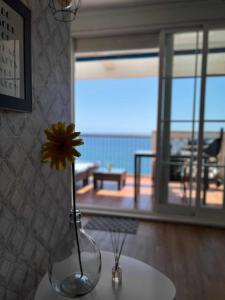 阿尔么丽亚Ático con terraza frente al mar Playa Zapillo的黄花花花在桌子上的花瓶