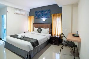 棉兰New Gentala Hotel Mitra RedDoorz的一间卧室配有一张大床、一张桌子和一张桌子