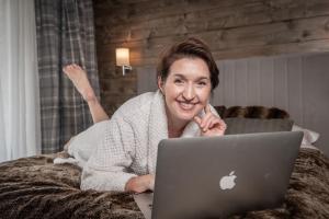 什切尔克Luxury Chalet Na Stromym Wzgórzu z sauną i balią的一位女士躺在床上,手提电脑