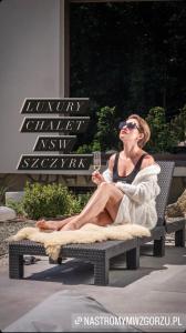 什切尔克Luxury Chalet Na Stromym Wzgórzu z sauną i balią的坐在椅子上的女人,喝一杯酒