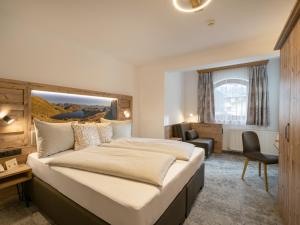 迈尔霍芬Hotel Garni Ferienhof的酒店客房带一张大床和一把椅子