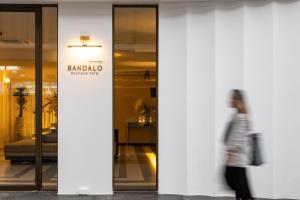 芭东海滩Bandalo Boutique Hotel的一位妇女走过一座建筑物,上面有标志