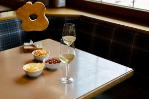 齐亚诺迪菲耶姆梅Suàn Hotel的一张桌子,上面放着两杯白葡萄酒和小吃