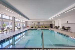 布兰普顿Home2 Suites By Hilton Toronto/Brampton, On的一座配有桌椅的酒店游泳池