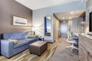 布兰普顿Home2 Suites By Hilton Toronto/Brampton, On的客厅配有蓝色的沙发和椅子