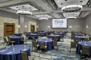 伯尼The Bevy Hotel Boerne, A Doubletree By Hilton的一个带蓝色桌椅和标志的宴会厅