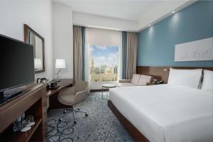 迪拜Hampton By Hilton Dubai Al Barsha的酒店客房配有一张床、一张书桌和一台电视。