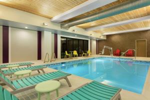 波特兰Home2 Suites By Hilton Portland Airport的游泳池位于酒店客房内,配有桌椅