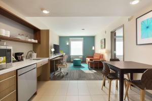 波特兰Home2 Suites By Hilton Portland Airport的厨房以及带桌椅的起居室。