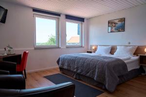 埃尔姆山麓克尼格斯卢特尔Hotel zur Post Ochsendorf的一间卧室设有一张大床和两个窗户。