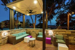 奥斯汀Hilton Garden Inn Cedar Park Austin的一个带绿色粉色家具和石墙的庭院