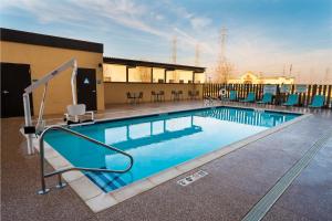 贝克斯菲尔德Home2 Suites Bakersfield的一座带蓝色椅子的游泳池和一座建筑