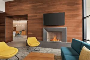 威尔明顿Homewood Suites By Hilton Wilmington Downtown的客厅设有壁炉和墙上的电视
