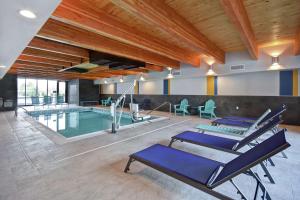 泰勒Home2 Suites By Hilton Taylor Detroit的一个带蓝色躺椅的室内游泳池和游泳池