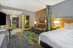 泰勒Home2 Suites By Hilton Taylor Detroit的酒店客房,配有床和沙发