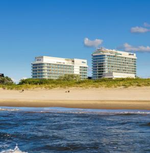 斯维诺乌伊希切Hilton Swinoujscie Resort And Spa的海滩上有两个高大的建筑