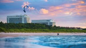 斯维诺乌伊希切Hilton Swinoujscie Resort And Spa的一个人在海滩上玩风筝