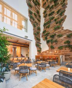 西棕榈滩Canopy West Palm Beach - Downtown的一间带桌椅的餐厅以及种植了植物的大墙