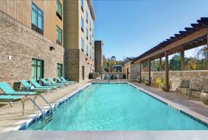 查尔斯顿Home2 Suites By Hilton Charleston Daniel Island, Sc的一座带躺椅的游泳池位于大楼旁