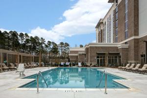 萨默维尔Homewood Suites By Hilton Summerville的一座带椅子的酒店游泳池以及一座建筑