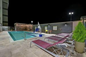 巴克艾Home2 Suites By Hilton Buckeye Phoenix的一个带躺椅的游泳池,晚上开放游泳池