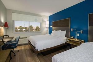格罗夫城Tru By Hilton Grove City Columbus的酒店客房设有两张床、一张书桌和一个窗户。
