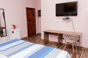 波多韦柳Guajará Palace Hotel的一间卧室配有书桌,墙上配有电视