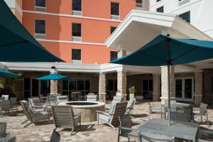 卡纳维拉尔角Home2 Suites By Hilton Cape Canaveral Cruise Port的一个带桌椅和遮阳伞的户外庭院。