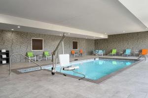 诺福克Home2 Suites By Hilton Norfolk Airport的游泳池位于酒店客房内,配有桌椅