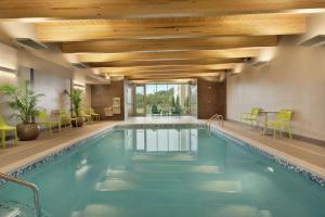 埃夫拉塔Home2 Suites By Hilton Ephrata的一座带绿椅和天花板的酒店游泳池