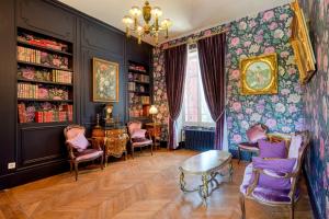 巴比松Le Petit Château de Barbizon au Bois du Mée的一间设有紫色椅子、一张桌子和书架的房间