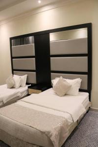 利雅德تاج الحمراء للاجنحة الفندقية Taj Al Hamra Hotel Suites的一间卧室配有两张带白色床单的床