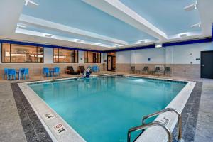 卡拉马祖Hilton Garden Inn Kalamazoo Downtown的一个带蓝色桌椅的大型游泳池