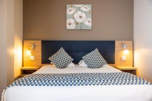 巴斯蒂亚Hôtel Le Bastia的一间卧室配有一张带蓝色和白色枕头的床