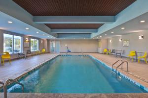 萨凡纳Home2 Suites By Hilton Savannah Midtown, Ga的一座游泳池,里面设有黄色的椅子和桌子