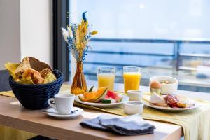 巴斯蒂亚Hôtel Le Bastia的一张桌子,早餐包括烤面包、水果和橙汁