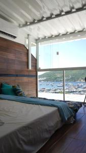 阿拉亚尔-杜卡布Suit's Bella Vista Arraial do Cabo的一张大床,位于带大窗户的房间里