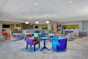迈尔斯堡Home2 Suites by Hilton Fort Myers Colonial Blvd的大堂设有五颜六色的椅子和桌子,位于图书馆