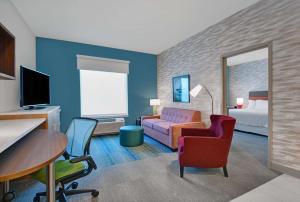 迈尔斯堡Home2 Suites by Hilton Fort Myers Colonial Blvd的酒店客房,配有一张床、一张桌子和椅子