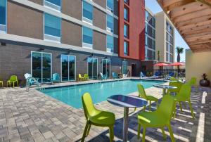 拉哥Home2 Suites By Hilton Largo, Fl的一座带桌椅的游泳池位于大楼旁