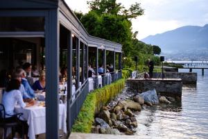 圣费利切德尔贝纳科Bella Hotel & Restaurant with private dock for mooring boats的餐馆,人们坐在河边的桌子旁