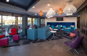 格伦代尔Tru By Hilton Phoenix Glendale Westgate的餐厅设有蓝色和红色的椅子和桌子