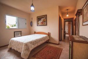 兰舒凯马杜Casa Fuchsia Régia em Rancho Queimado/SC的一间卧室设有一张大床和一个窗户。
