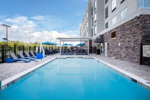 北港Hampton Inn & Suites North Port, Fl的一座带蓝色椅子的游泳池和一座建筑