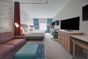 罗利Home2 Suites By Hilton Raleigh North I-540的一间配备有沙发及电视的酒店客房