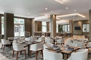 亚特兰大Embassy Suites by Hilton Atlanta Midtown的用餐室配有桌子和白色椅子