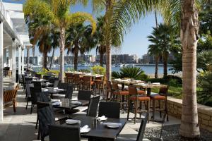 洛杉矶Jamaica Bay Inn Marina Del Rey Tapestry Collection by Hilton的一间设有桌椅的餐厅,种植了棕榈树