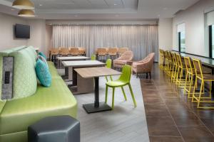 奥兰多Home2 Suites by Hilton Orlando Downtown, FL的一间设有桌椅和绿色沙发的等候室
