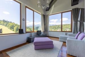 普雷代亚尔Vila Etiquette的客厅设有大窗户和紫色家具